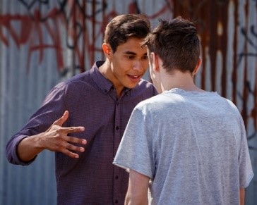 A young man looking angry and yelling at another young man