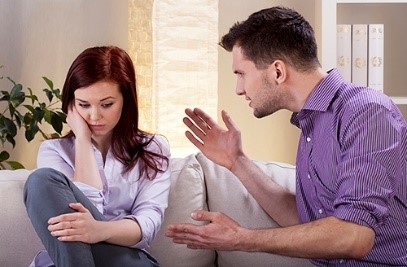 A man looking angry, talking to a woman who is looking down with her head in her hands