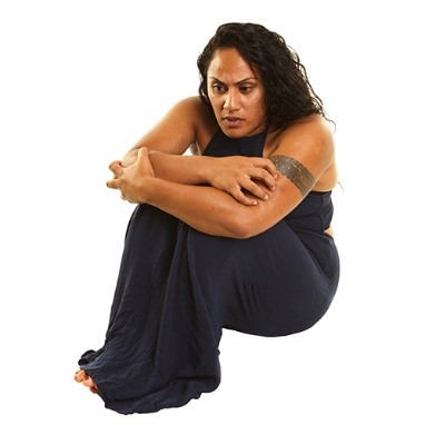 A woman sitting on the ground with her arms over her legs and her head down