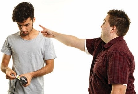 A man pointing at another man, who is getting money out of his wallet
