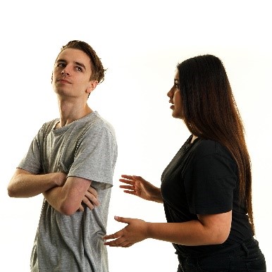 A young woman trying to talk to a young man, but the man isn’t listening. He has his arms crossed.